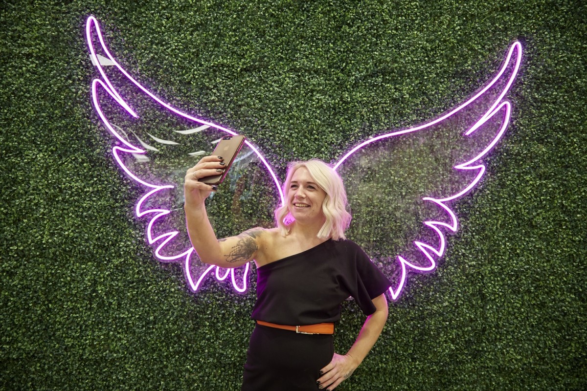 Creative Stylist Laura Truscott takes a selfie in front of pink angel wings
